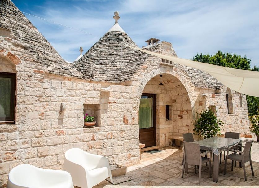 Almapetra Trulli Resort in Locorotondo, stone trullo courtyard with outdoor dining area