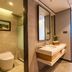 Lijiang International Hotel in Lijiang bathroom with glass shower, toilet, vanity sink, and doorway to bedroom