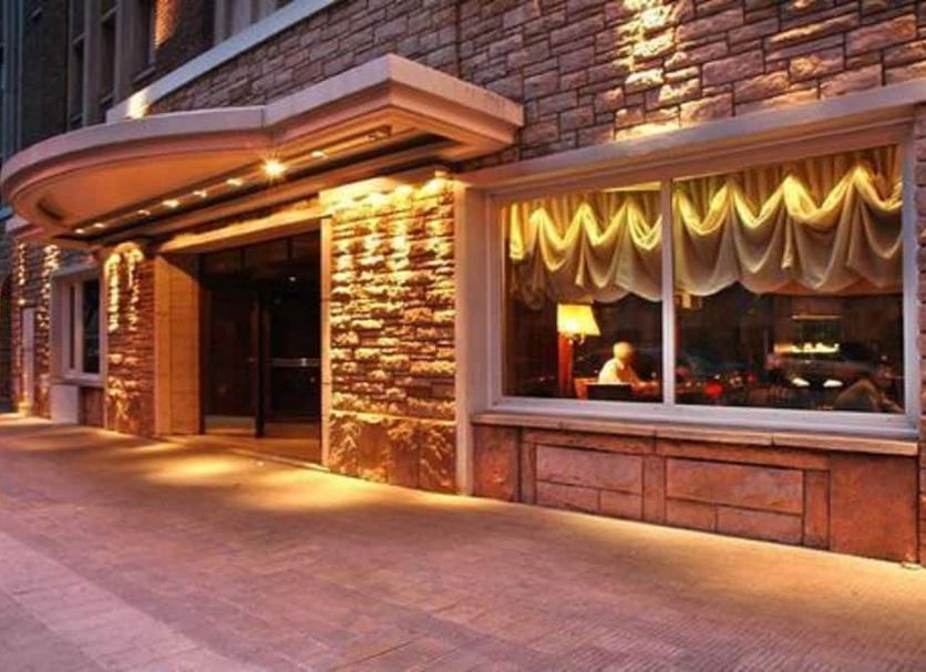 Austral Bahia Blanca Hotel in Bahía Blanca, stone facade entrance with warm exterior lighting at dusk