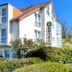 Hotel Garni Niedernhausen in Niedernhausen, white 3-story hotel with sloped roof and greenery