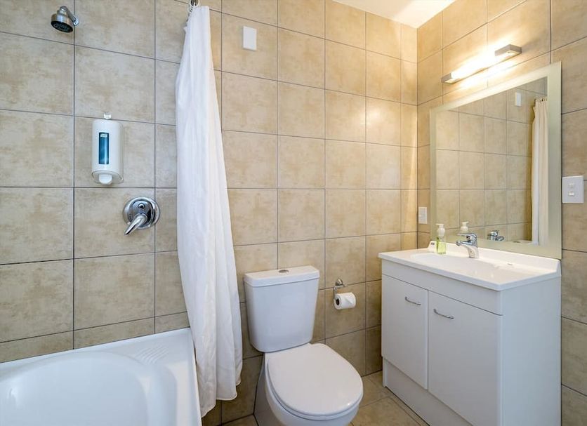 Finns Paekakariki bathroom with shower, toilet, sink and mirror in Paekakariki