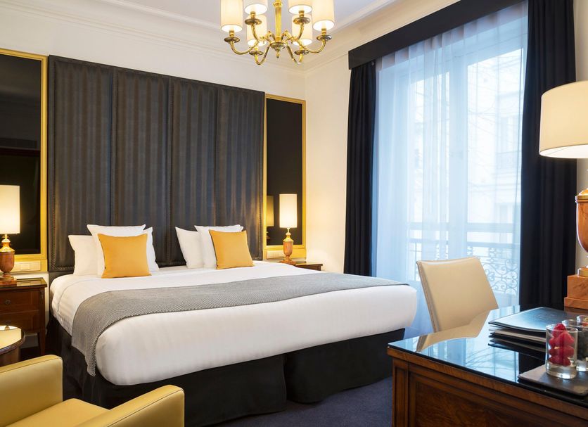 Melia Paris Champs Elysees guest room in Paris with a king bed, chandelier, and balcony doors