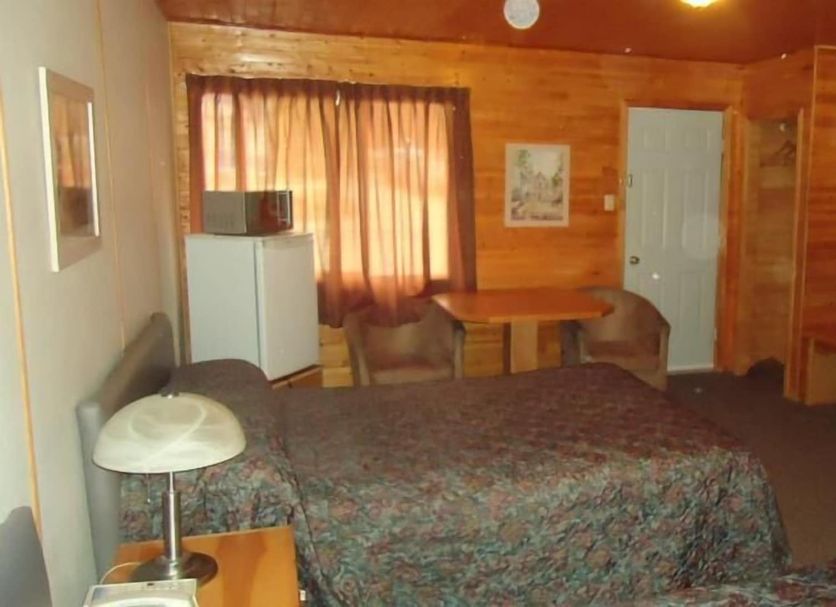 The Dreamland Motel Moose Jaw guest room with bed, table, desk and wood-paneled walls