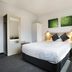 Nightcap at St Albans Hotel bedroom with queen bed, desk, mirror and green wall art in Saint Albans