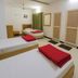 Stayguru Usha Residency Bhuj twin room with three single beds, green curtains and wall mirrors