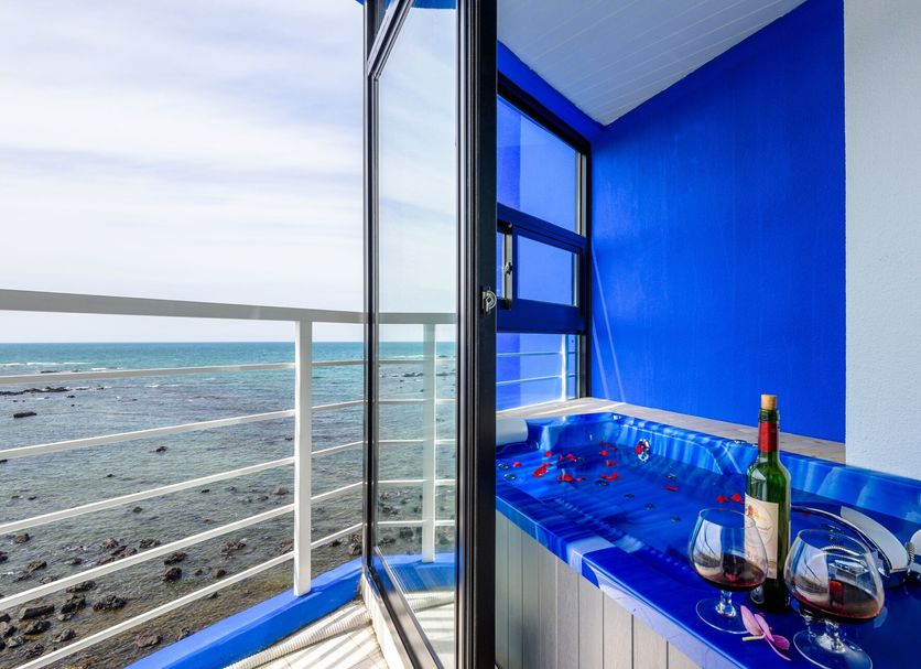 On the Sea Pension in Jeju City balcony with ocean view and a small table set for drinks