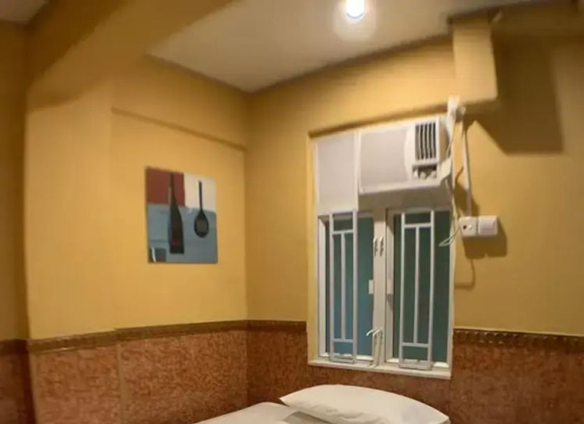 Hk Peaceful Guesthouse Hong Kong compact guest room with single bed, window air conditioner and tiled walls
