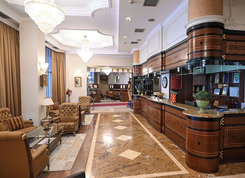 Stone Bridge Hotel Skopje lobby with polished marble floor, chandelier lighting, and wood reception desk