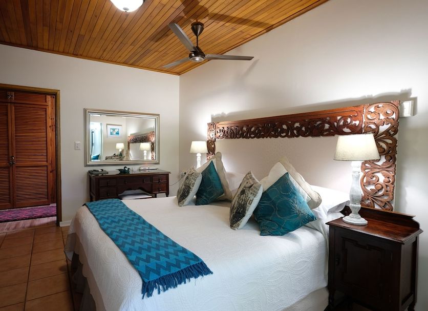 Santa Lucia Guest House in Saint Lucia bedroom with carved headboard, king bed and ceiling fan