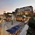 The Capital Menlyn Maine in Pretoria: outdoor courtyard with umbrellas, lit trees and modern hotel buildings