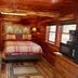 Log Cabin Inn in Eureka Springs guest room with log walls, plaid bed, and wood-paneled ceiling