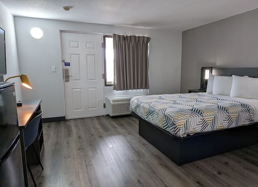 Motel 6 Leominster Ma guest room with king bed, desk, window and wood-look flooring in Leominster
