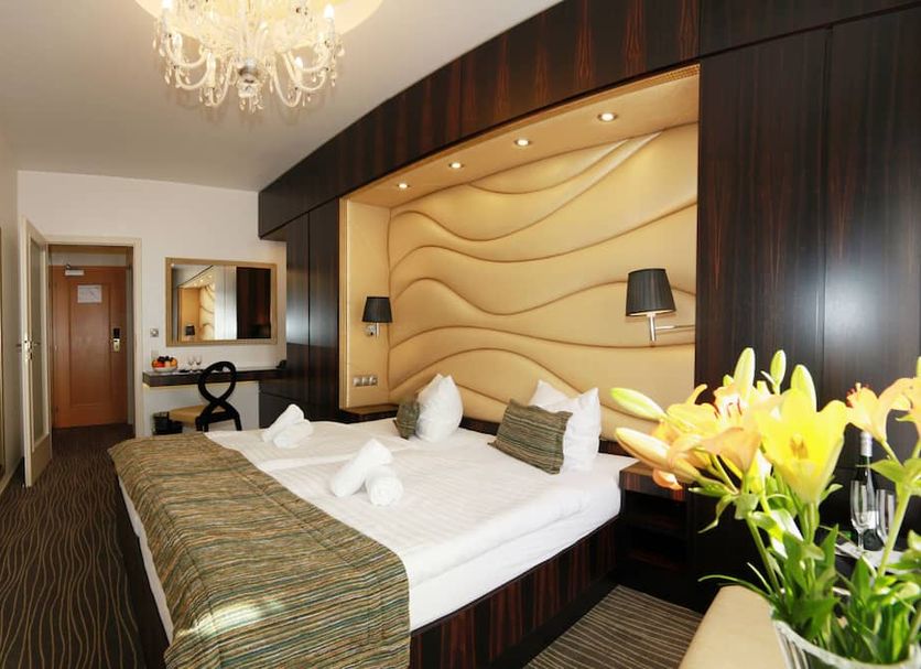 Hotel Ambiente Wellness & Spa in Carlsbad guest room with a large bed, chandelier, and yellow flowers