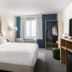 Spark by Hilton Merrillville guest room with king bed, window, seating area, and open wardrobe