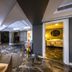 B Loft Hotel in Bursa: modern lounge area with seating, TV, and adjacent warmly lit restroom entrance