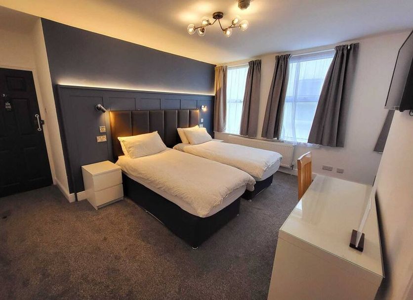 At Caledonia, Douglas hotel room with two twin beds, bedside lamps, windows and a wall-mounted TV