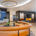 Cambria Hotel Spokane Airport lobby with curved tan seating, front desk, fireplace and blue accent wall in Spokane