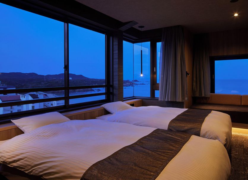 Resort Hills Toyohama Soranokaze in Toba with twin beds and ocean-view windows at dusk