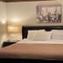 Maxwelton Braes Lodge guest room in Baileys Harbor with a king bed, bedside lamps, and wall art