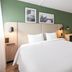 Campanile Nature - Mont De Marsan guest room with double bed, green accent wall and desk in Mont-de-Marsan