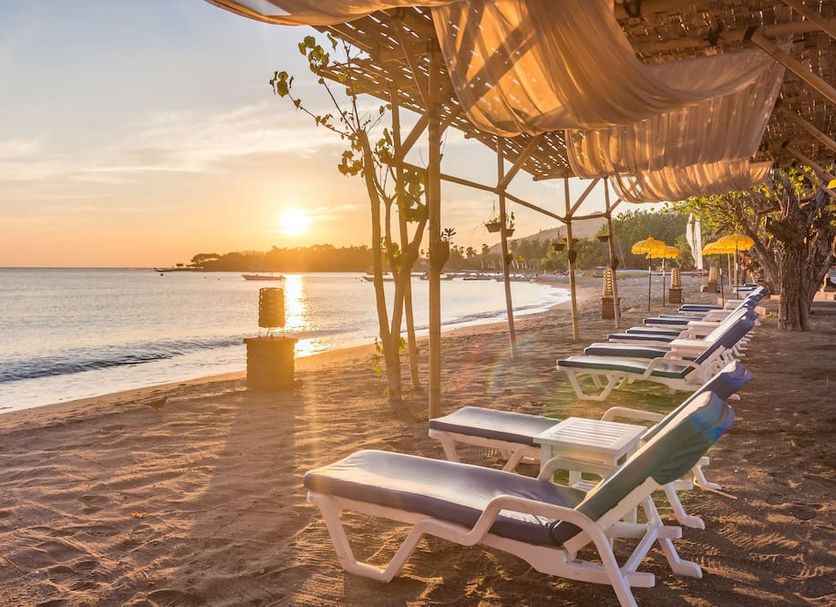 Sunset beach loungers at Amertha Bali Villas in Gerokgak beside calm ocean water