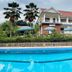 Infinity Hotel Kampala in Kampala with a pool in front of a two-story building and palm trees