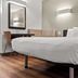 Studio 6 San Luis Obispo Ca South room with queen bed, desk, chair, wall mirror, and wood flooring