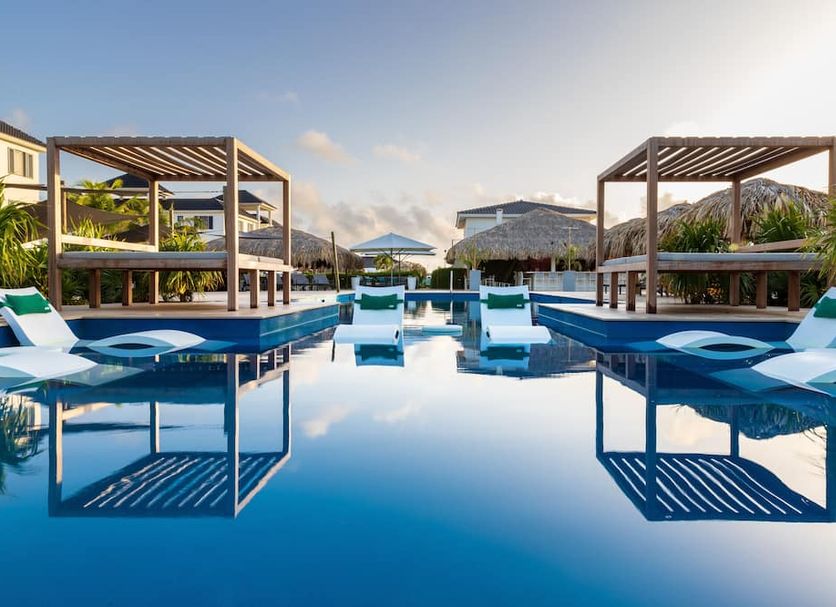 Grand Windsock Bonaire in Kralendijk with a serene pool, lounge chairs, and cabanas reflecting in water