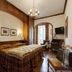 Hotel De La Poste in Cortina d'Ampezzo guest room with carved wood paneling and chandelier