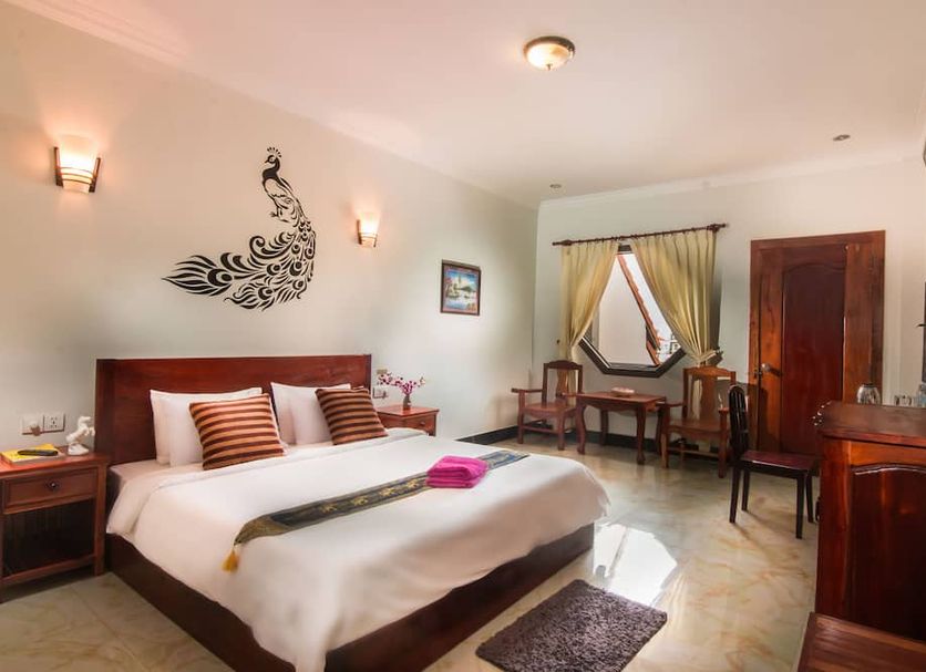 Angkor Udom Guesthouse in Siem Reap guest room with king bed, wall art, desk and window seating