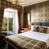 Loch Kinord Hotel, Aboyne: plaid bedding in a guest room with French doors to a balcony
