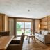 Residence Cesa Sassela in Ortisei: rustic living room with sofa, dining table and balcony doors