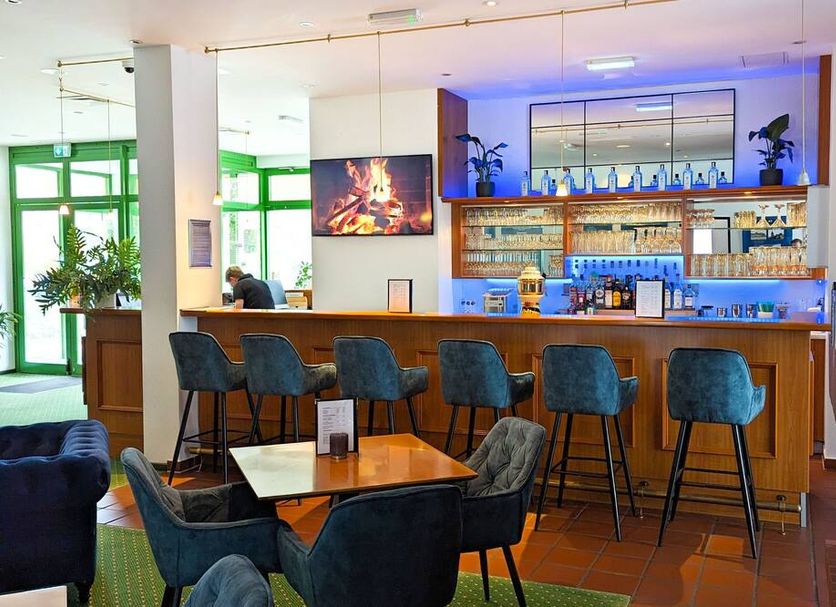 Acron-Hotel Quedlinburg bar area with high stools, tables and shelves of bottles in Quedlinburg
