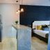 Rio Suites in Tijuana: modern suite with kitchenette, marble island, and bed beside a dark textured wall.