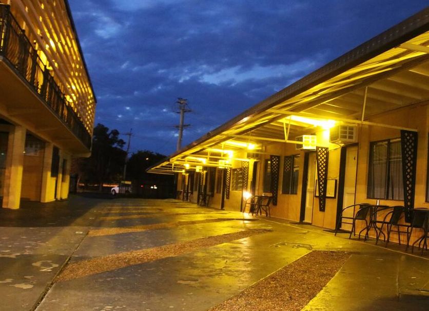 Bourbong Street Motel in Bundaberg at dusk, showing a lit motel courtyard and covered walkways