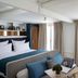 Hotel Louvre Montana in Paris guest room with bed, sofa, desk, and bright window view