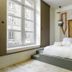 Hôtel Préfecture in Limoges, minimalist bedroom with raised bed, large windows and abstract wall hanging