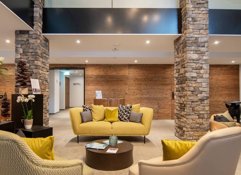 Walliserhof Grand-Hotel & Spa Relais & Châteaux lobby seating area in Saas-Fee with yellow sofas and stone columns