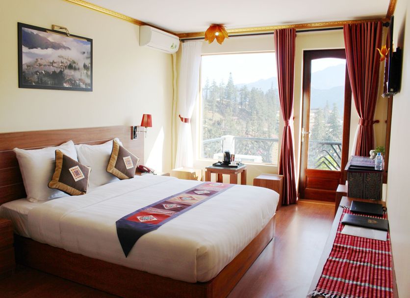 Sapa Dragon Hotel guest room with king bed, large window, balcony door and mountain view in Sa Pa