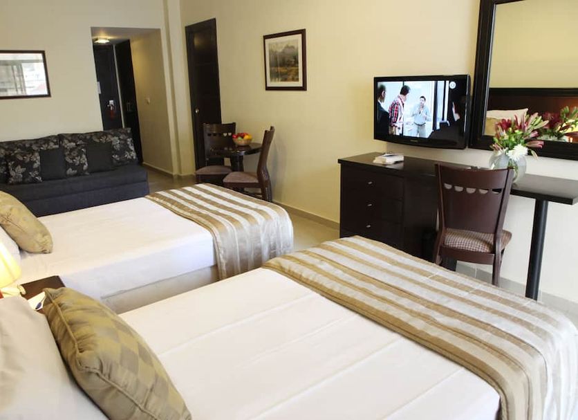 Mozart Hotel Beirut guest room with two beds, TV, desk and chair