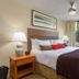 West Coast Suites At Ubc in Vancouver guest room with king bed, bedside lamps, and large window view of trees.