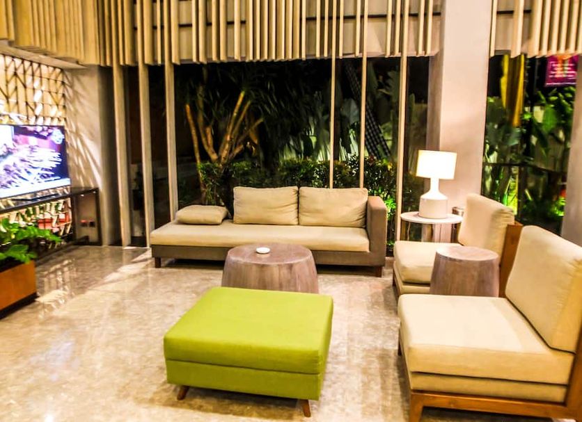 The Nest Hotel Nusa Dua, South Kuta lounge with sofas, ottoman, lamp and tropical greenery
