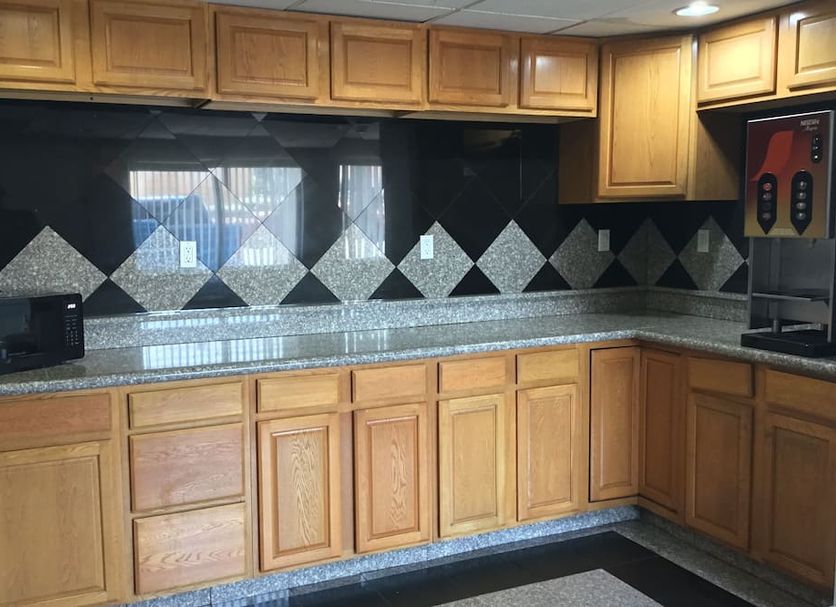 Motel 6 El Paso West kitchen area with wood cabinets, granite counter, and black diamond backsplash