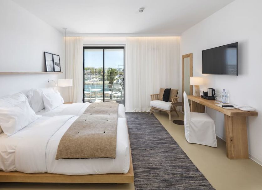 Lagos Avenida Hotel guest room with bed, desk, TV and balcony view over the pool in Lagos