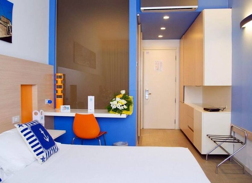 Hotel Kaos in Agrigento guest room with bed, desk, chair, and bright blue accent wall