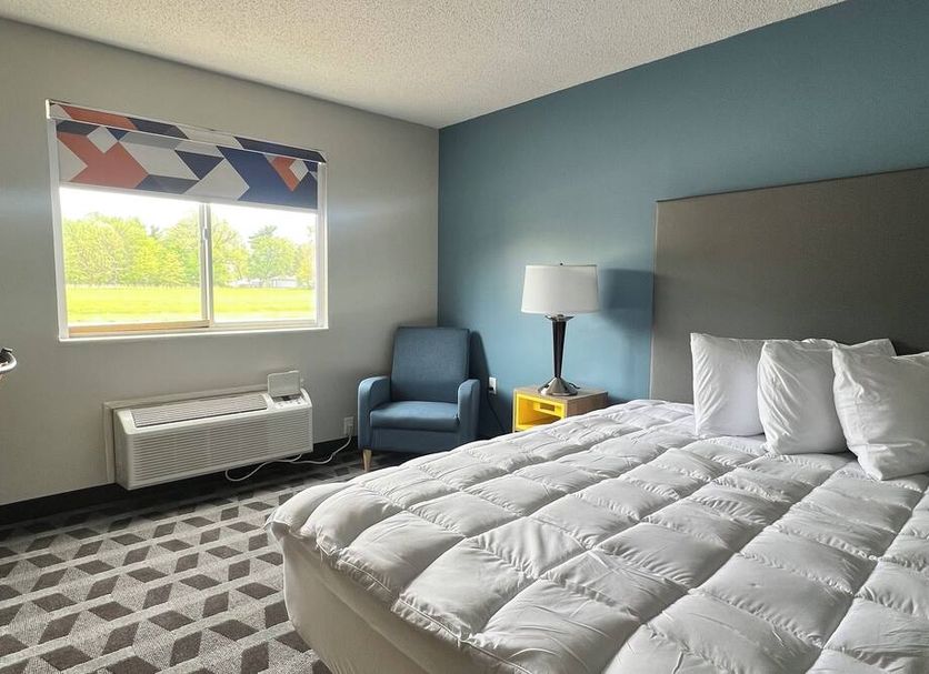 Lakewood Inn & Suites in Dowagiac guest room with bed, armchair, window view and lamp