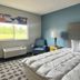 Lakewood Inn & Suites in Dowagiac guest room with bed, armchair, window view and lamp