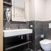 Bathroom at B&B Hotel Roma Fiumicino Aeroporto Fiera 2 with sink, toilet, and dark tiled walls in Fiumicino.