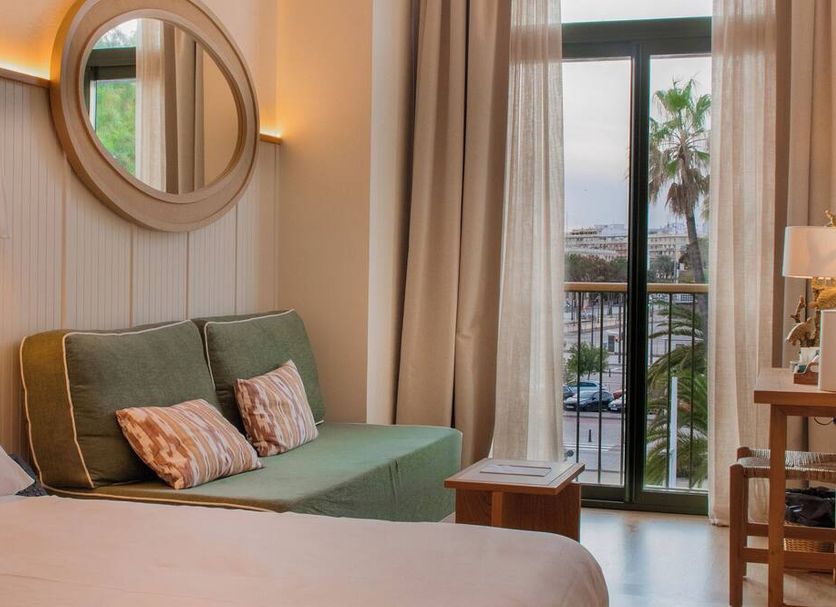 Casa Bassa in Valencia room with green daybed, round mirror, balcony doors and palm view