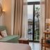 Casa Bassa in Valencia room with green daybed, round mirror, balcony doors and palm view